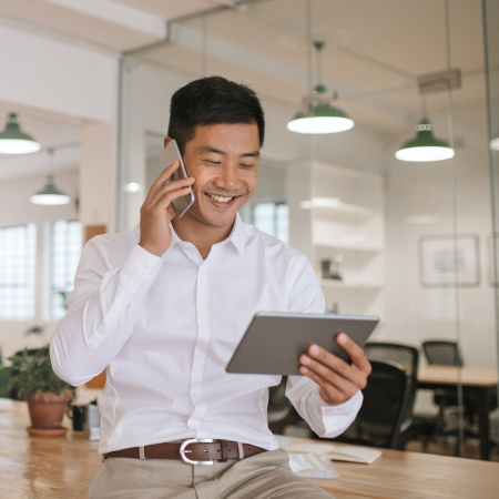 business man on phone, looking at tablet
